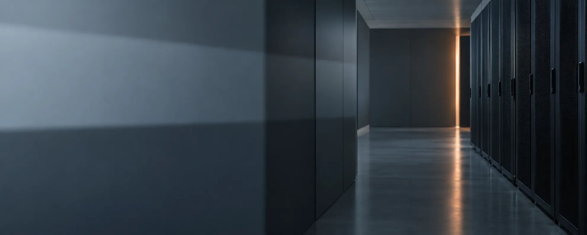 A dimly lit data center corridor with a single warm light at the far end